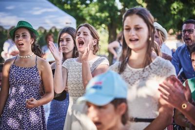 Un grand groupe de personnes souriantes levant les bras, rassemblées dans un parc pour une célébration.