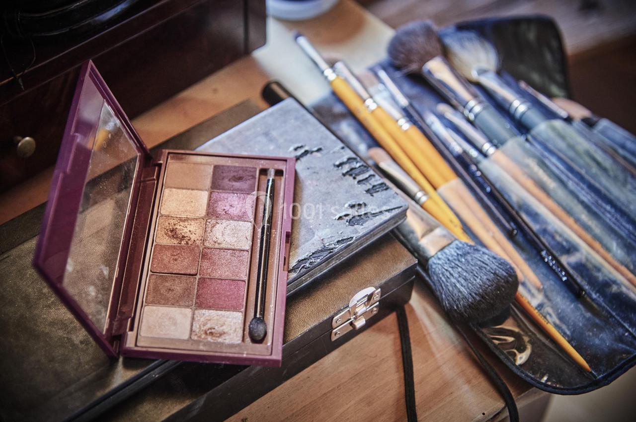 Palette de maquillage ouverte avec pinceaux disposés sur une table en bois.