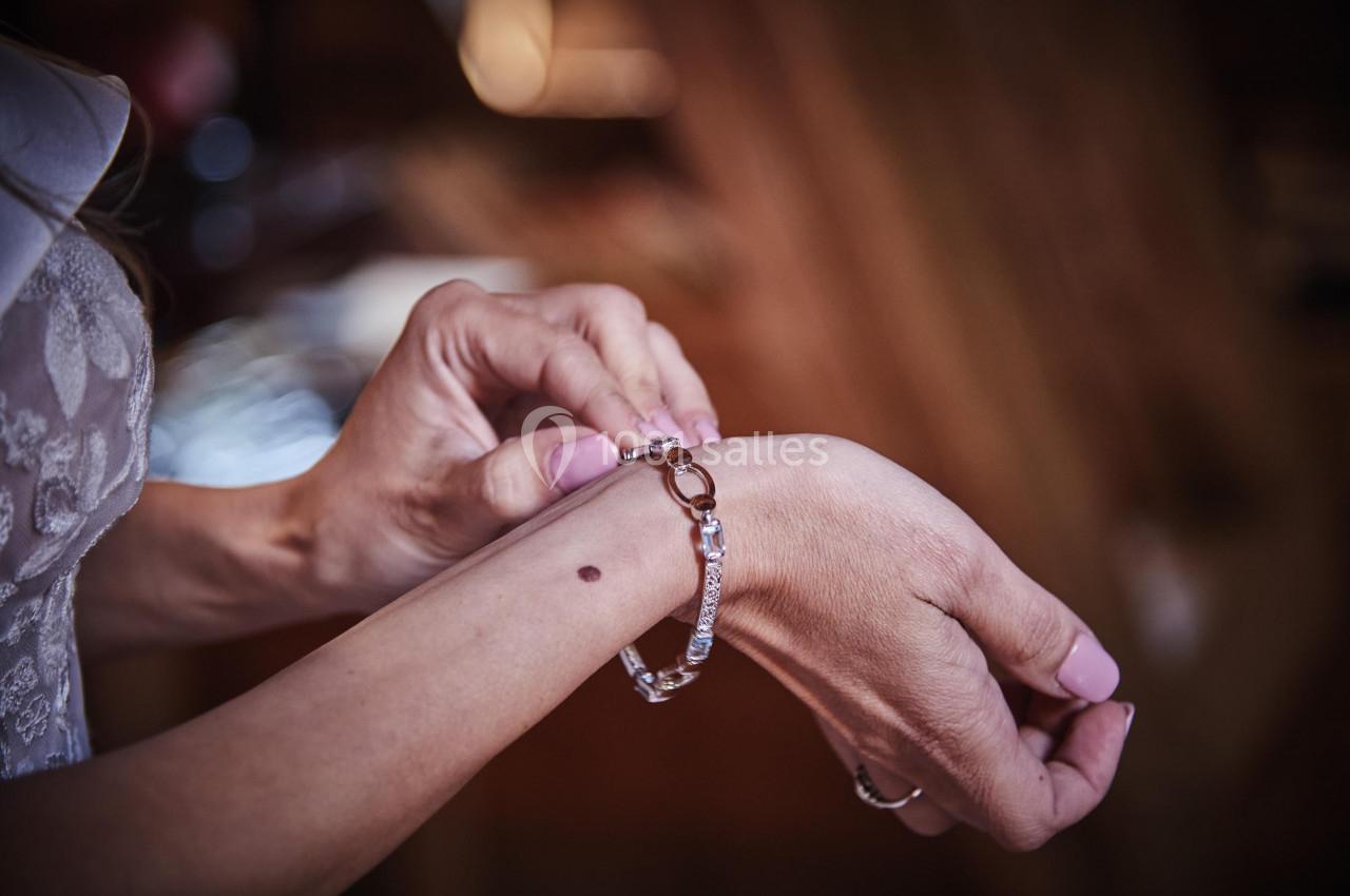 Une personne attache un bracelet argenté à son poignet, en arrière-plan flou.