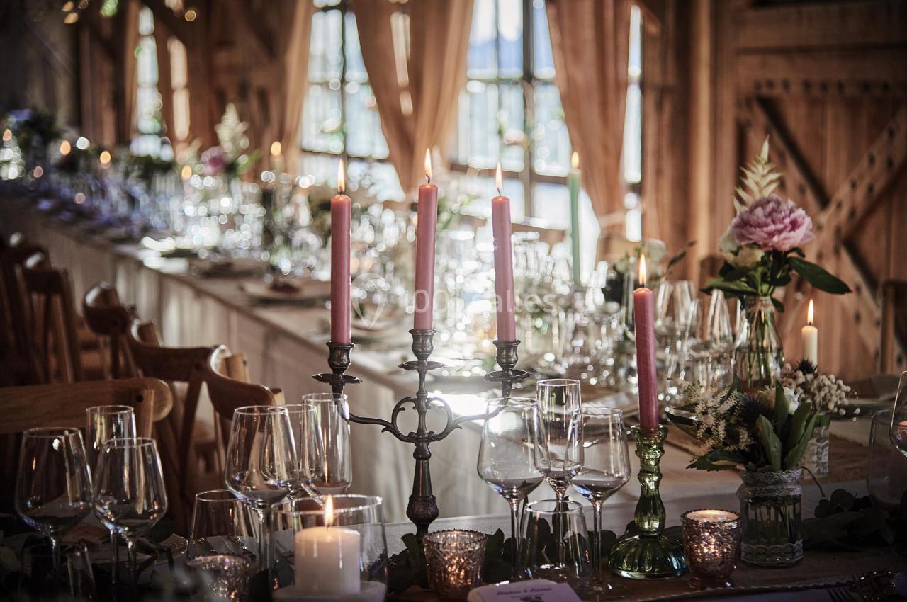 Table décorée pour un dîner élégant avec chandeliers, verres à vin et fleurs dans une ambiance chaleureuse.