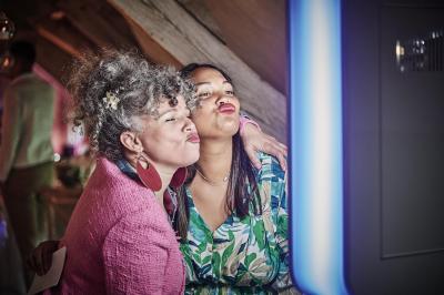 Un grand groupe de personnes souriantes levant les bras, rassemblées dans un parc pour une célébration.