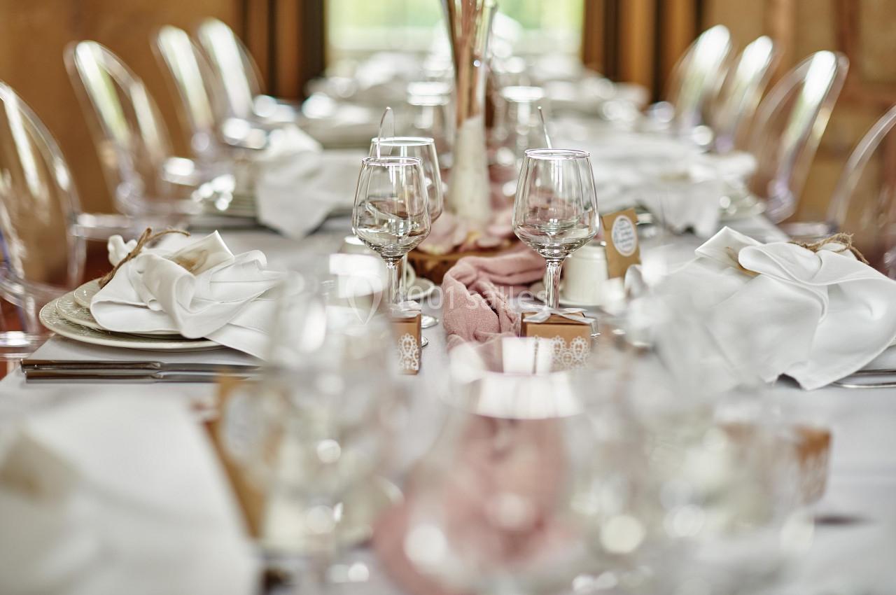 Table élégamment dressée avec nappes blanches, serviettes pliées, verres à pied et décorations raffinées.