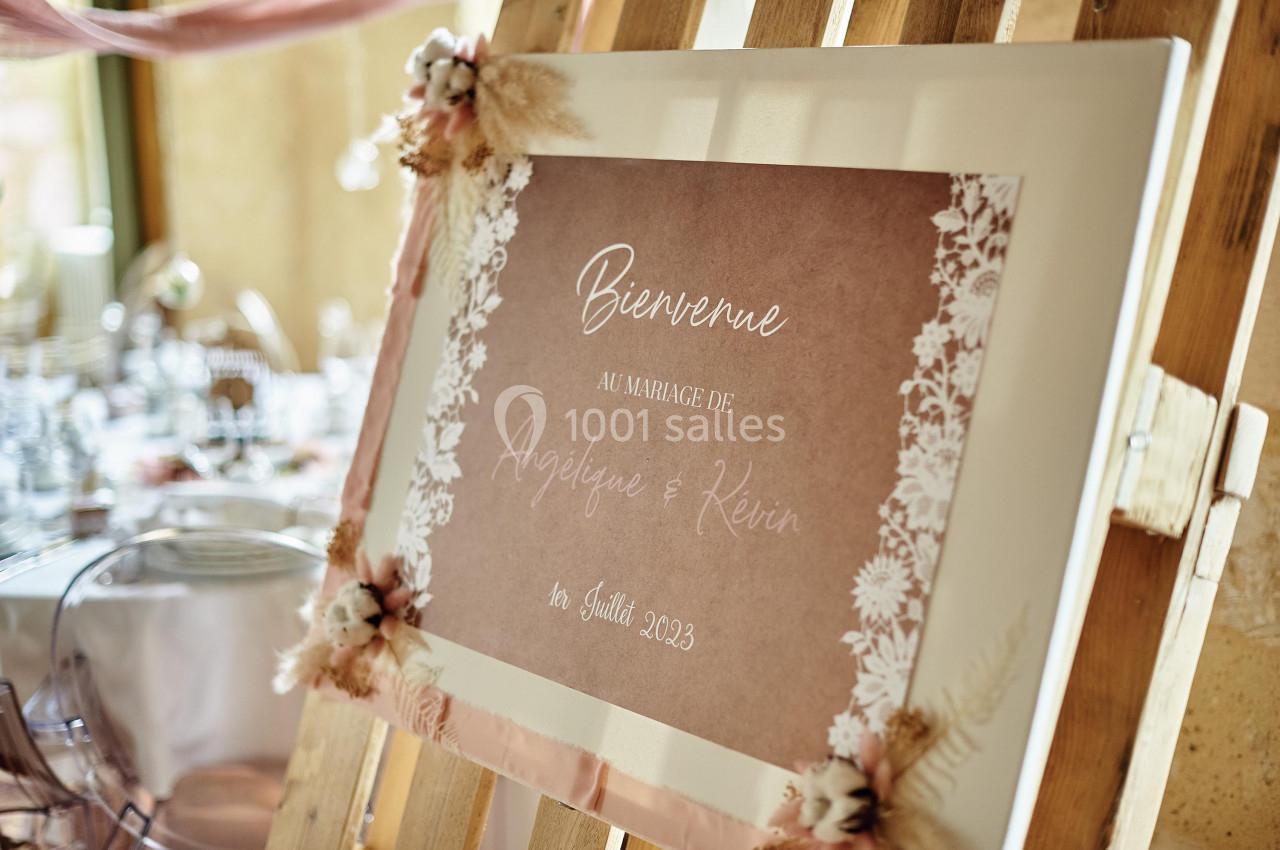 Panneau de bienvenue au mariage d'Angéline et Kévin, décoré de fleurs séchées et posé sur un chevalet en bois.