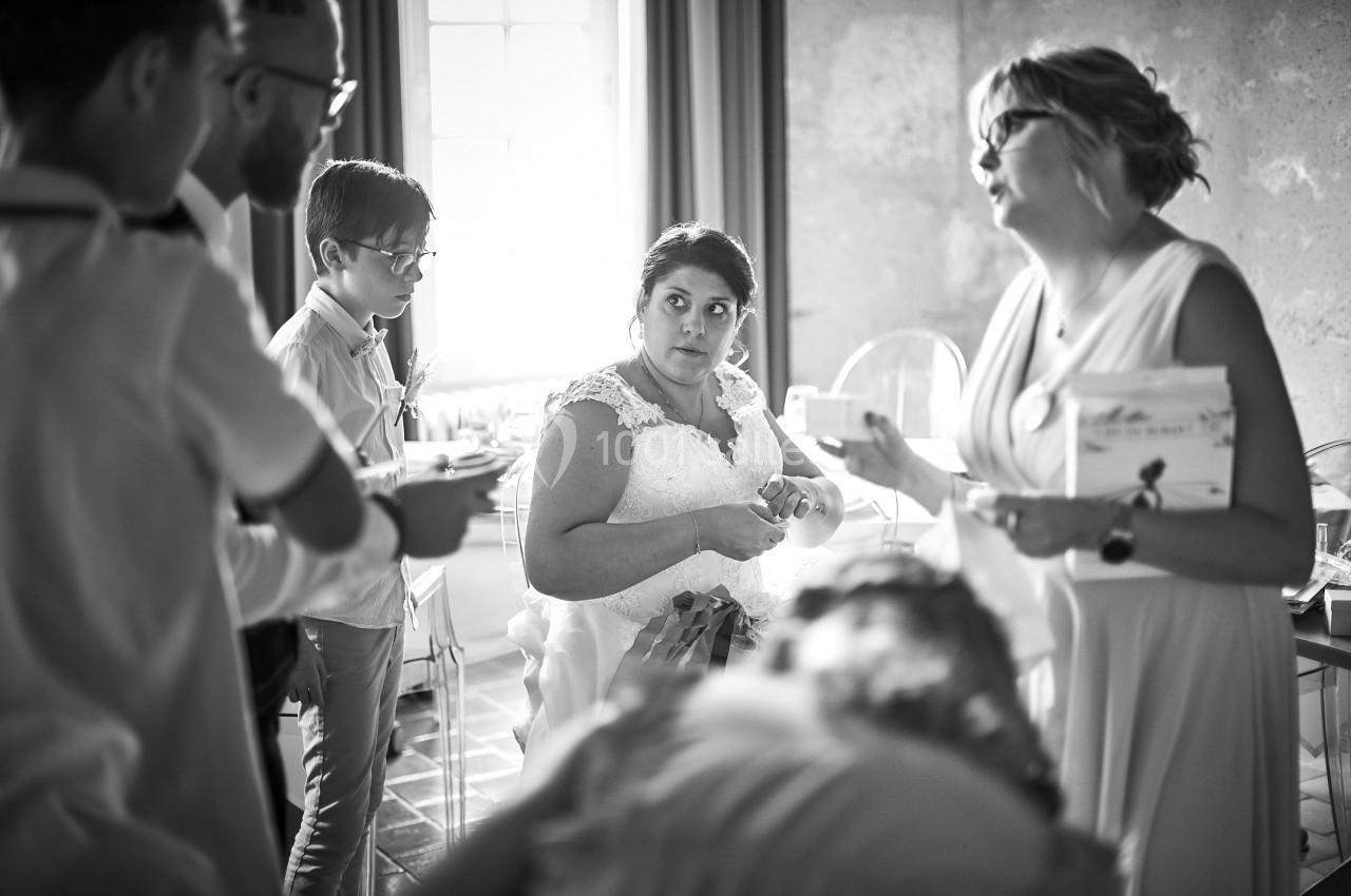 Une mariée entourée de plusieurs personnes dans une pièce lumineuse, échangeant et se préparant.