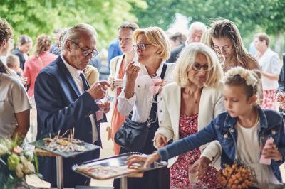 Un grand groupe de personnes souriantes levant les bras, rassemblées dans un parc pour une célébration.