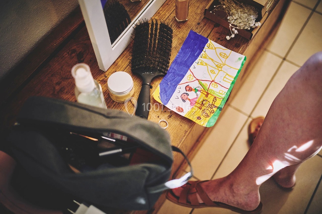 Dessin d'enfant coloré posé sur une table en bois avec des objets divers, dont une brosse et des produits de soin.