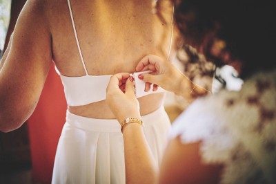 Un couple de mariés s'embrasse tendrement près d'un étang, entouré de verdure, la mariée tenant un bouquet coloré.
