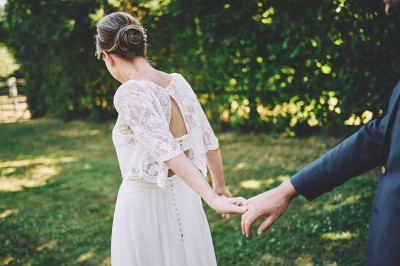 Un couple de mariés s'embrasse tendrement près d'un étang, entouré de verdure, la mariée tenant un bouquet coloré.