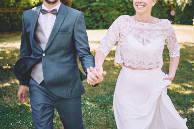Un couple de mariés s'embrasse tendrement près d'un étang, entouré de verdure, la mariée tenant un bouquet coloré.