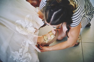 Un couple de mariés s'embrasse tendrement près d'un étang, entouré de verdure, la mariée tenant un bouquet coloré.