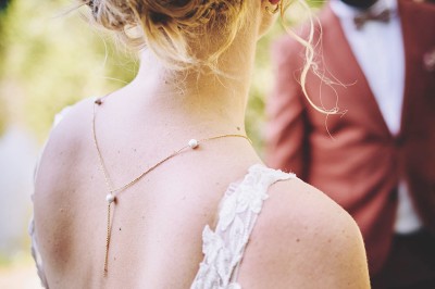 Un couple de mariés s'embrasse tendrement près d'un étang, entouré de verdure, la mariée tenant un bouquet coloré.