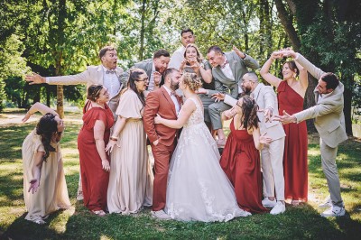Un couple de mariés s'embrasse tendrement près d'un étang, entouré de verdure, la mariée tenant un bouquet coloré.