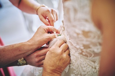 Un couple de mariés s'embrasse tendrement près d'un étang, entouré de verdure, la mariée tenant un bouquet coloré.