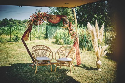 Un couple de mariés s'embrasse tendrement près d'un étang, entouré de verdure, la mariée tenant un bouquet coloré.