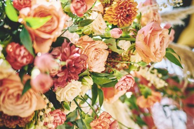 Un couple de mariés s'embrasse tendrement près d'un étang, entouré de verdure, la mariée tenant un bouquet coloré.