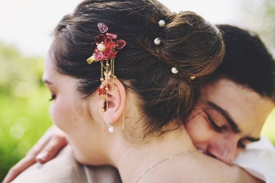 Un couple de mariés s'embrasse tendrement près d'un étang, entouré de verdure, la mariée tenant un bouquet coloré.