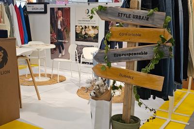 Stand d'exposition avec un panneau en bois indiquant ’Style urbain’, ’Confortable’, ’Éco-responsable’ et ’Durable’.