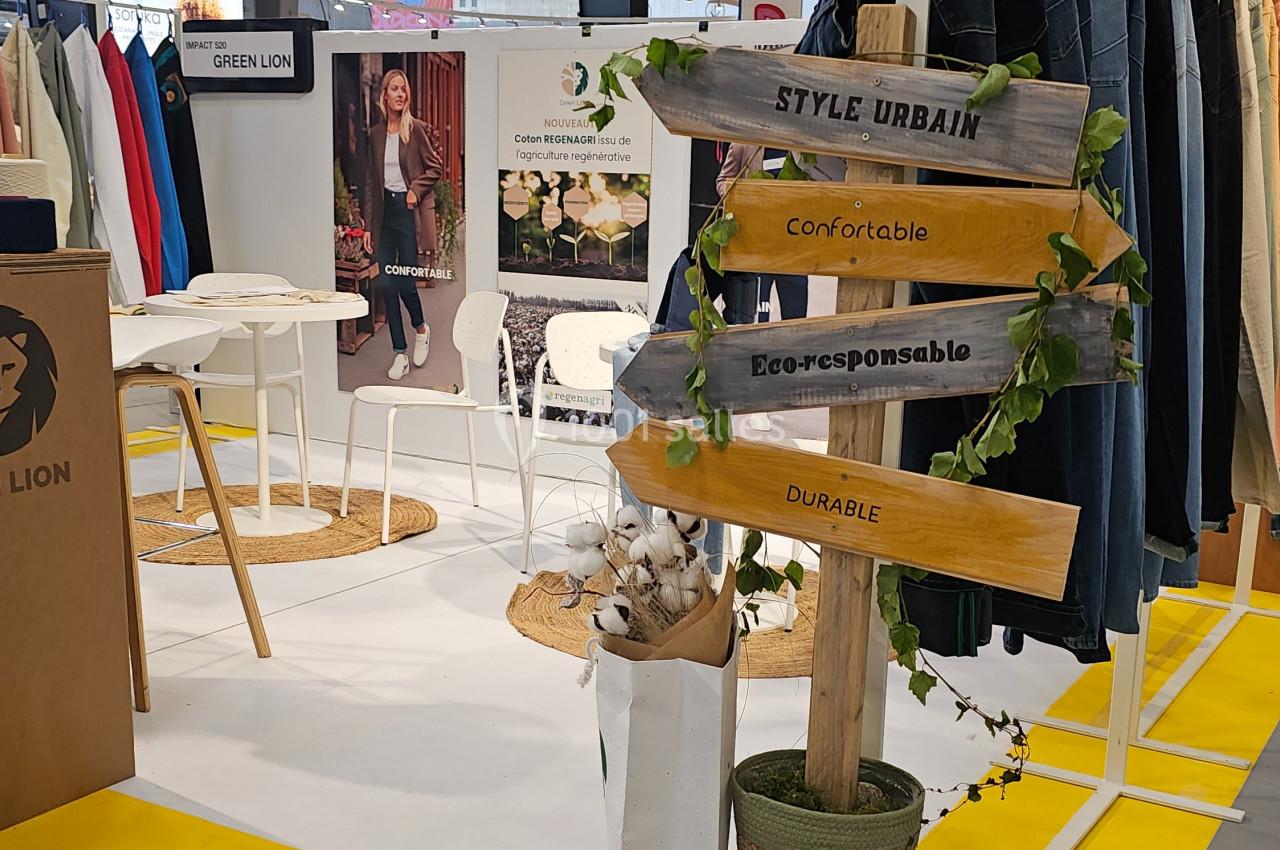 Stand d'exposition avec un panneau en bois indiquant ’Style urbain’, ’Confortable’, ’Éco-responsable’ et ’Durable’.