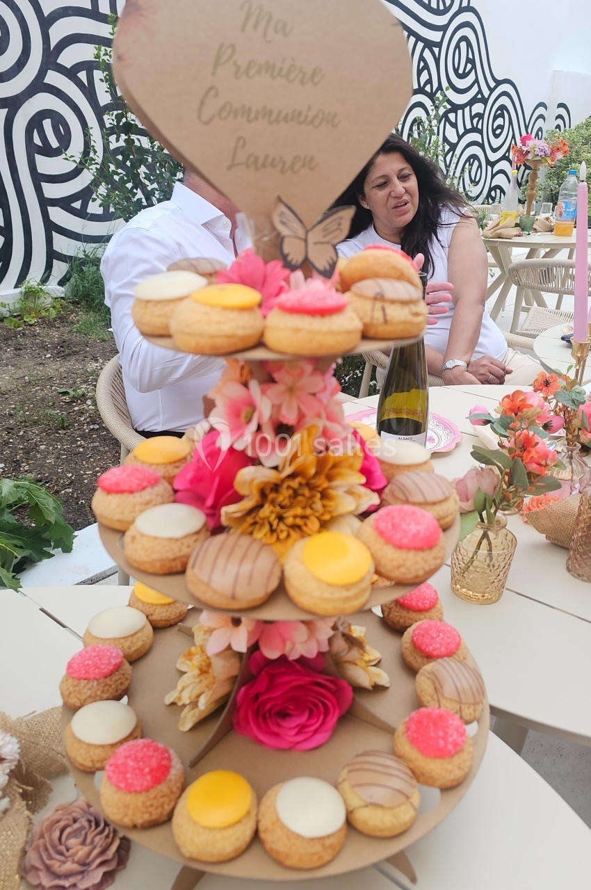 Présentoir de pâtisseries colorées décoré de fleurs, avec une inscription pour une première communion.