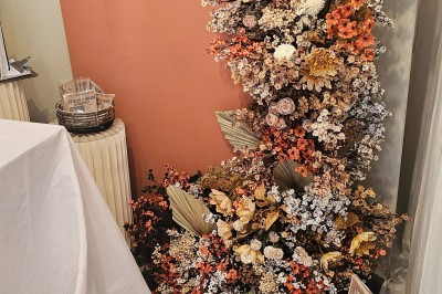 Présentoir en bois décoré de fleurs et de choux colorés, lors d'une célébration en extérieur.