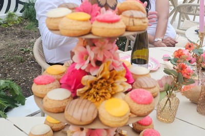 Présentoir en bois décoré de fleurs et de choux colorés, lors d'une célébration en extérieur.