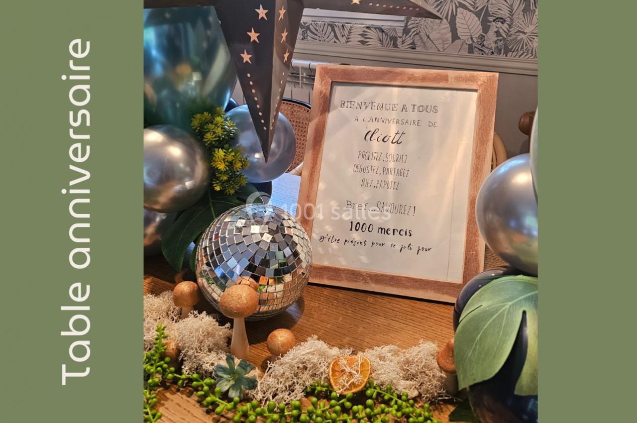 Décoration de table d'anniversaire avec boule disco, plantes, ballons et cadre contenant un message de remerciement.