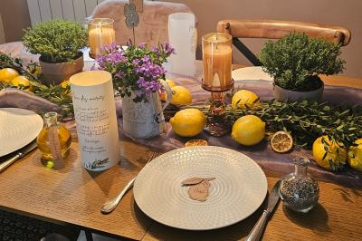 Arrangement floral avec des fleurs roses et blanches, entouré de petits sachets cadeaux en tissu et jute sur une table.