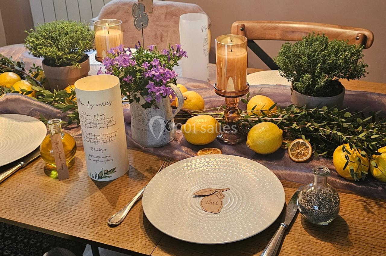 Table décorée avec des citrons, plantes aromatiques, bougies et vaisselle élégante dans une ambiance chaleureuse.