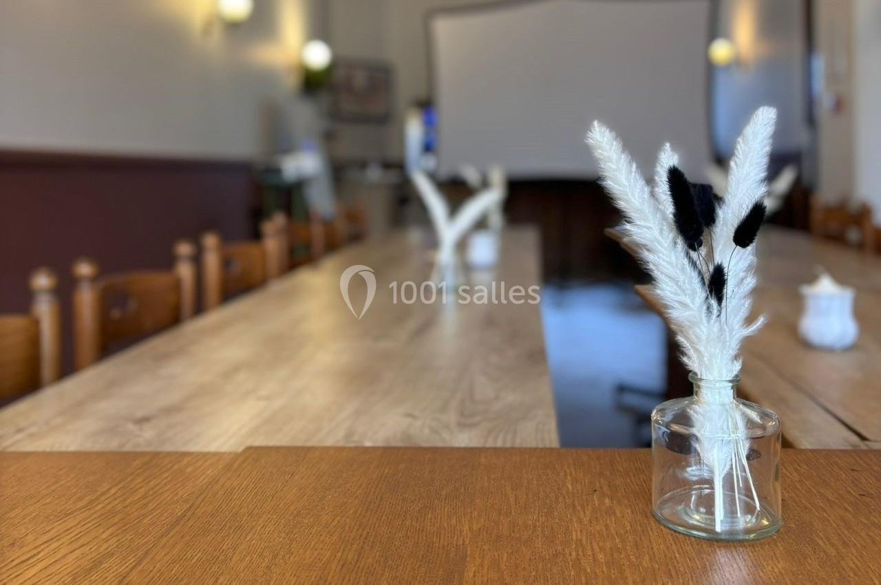 Branchettes décoratives blanches et noires dans un vase en verre sur une table en bois dans une salle lumineuse.