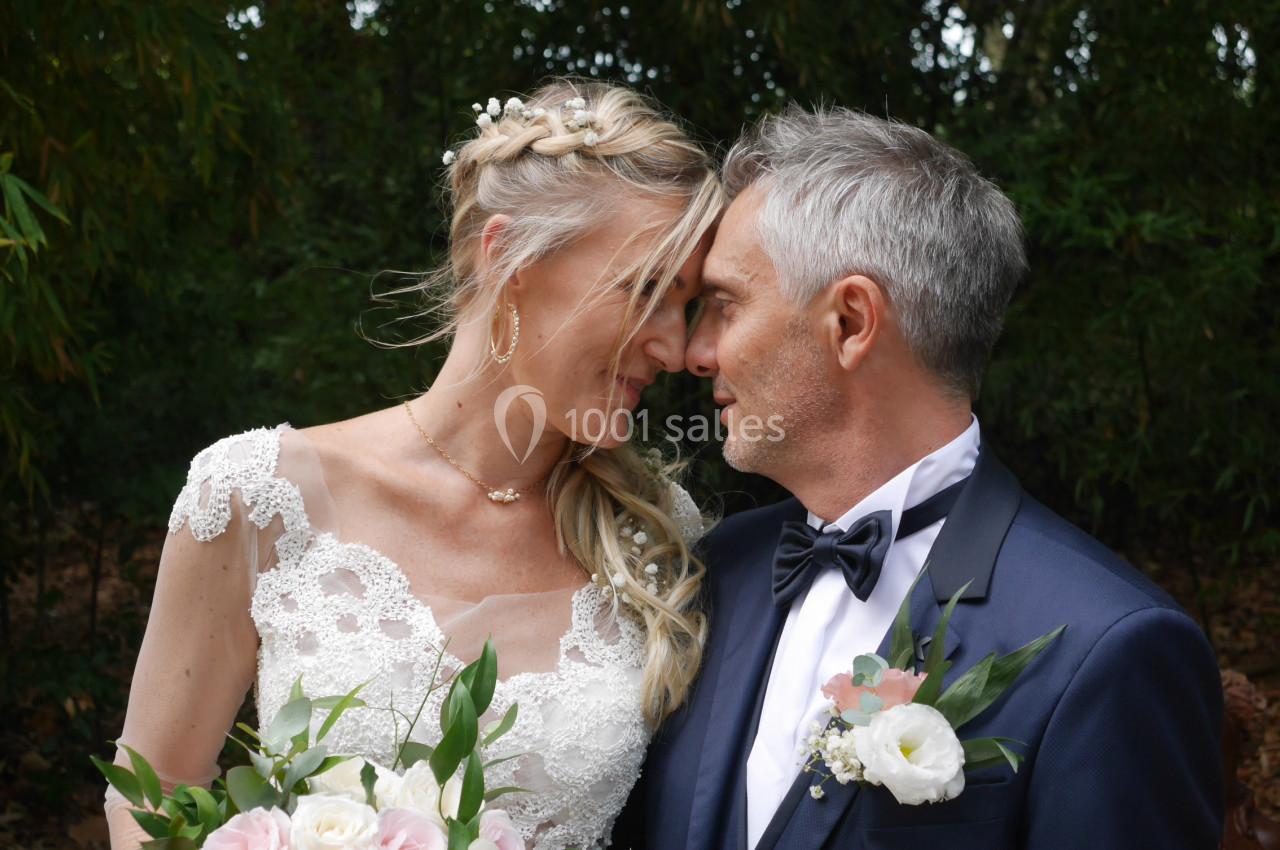 Un couple en tenue de mariage se regarde tendrement dans un jardin verdoyant.