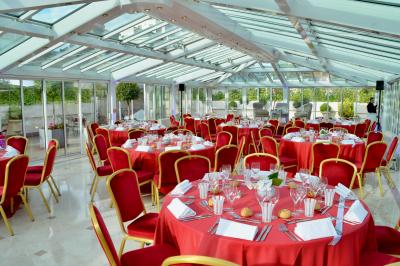 Miniature Traiteur Saint-Cloud (Hauts-de-Seine) - Aux Jardins des Sens #8 Façade illuminée d'un bâtiment élégant au crépuscule, avec un jardin et des invités rassemblés devant.