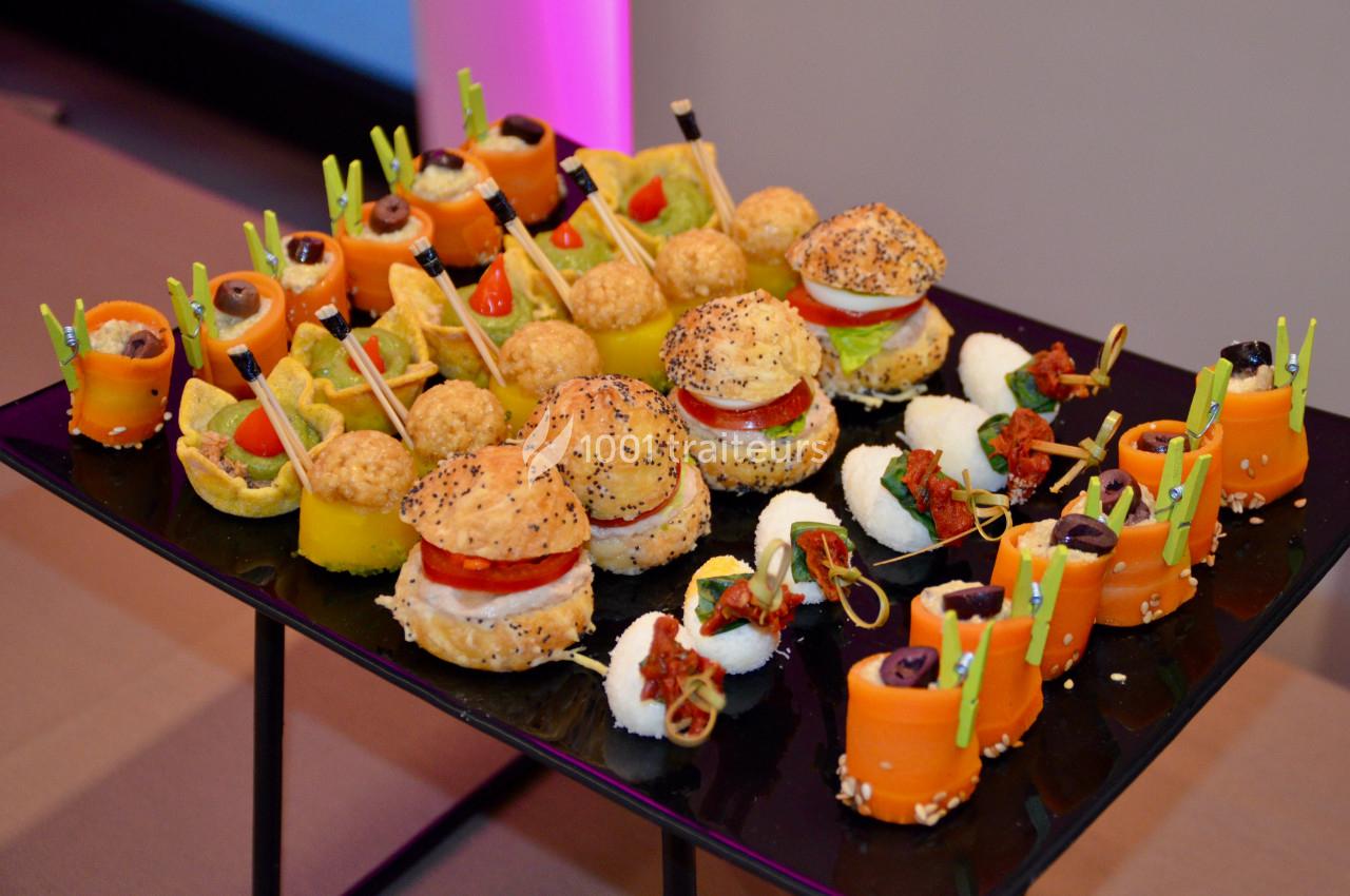 Plateau de bouchées apéritives variées comprenant mini-burgers, roulés de légumes et autres amuse-bouches colorés.