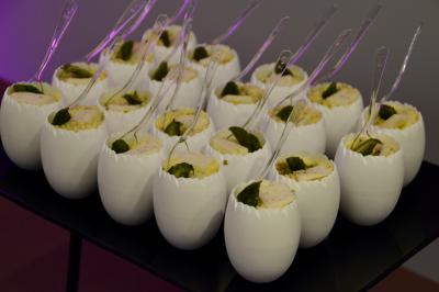 Miniature Traiteur Saint-Cloud (Hauts-de-Seine) - Aux Jardins des Sens #11 Façade illuminée d'un bâtiment élégant au crépuscule, avec un jardin et des invités rassemblés devant.