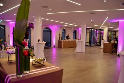 Miniature Traiteur Saint-Cloud (Hauts-de-Seine) - Aux Jardins des Sens #12 Façade illuminée d'un bâtiment élégant au crépuscule, avec un jardin et des invités rassemblés devant.