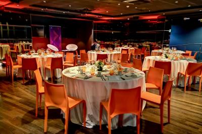 Miniature Traiteur Saint-Cloud (Hauts-de-Seine) - Aux Jardins des Sens #25 Façade illuminée d'un bâtiment élégant au crépuscule, avec un jardin et des invités rassemblés devant.