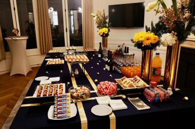 Miniature Traiteur Saint-Cloud (Hauts-de-Seine) - Aux Jardins des Sens #32 Façade illuminée d'un bâtiment élégant au crépuscule, avec un jardin et des invités rassemblés devant.
