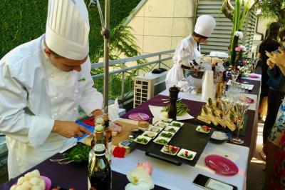 Miniature Traiteur Saint-Cloud (Hauts-de-Seine) - Aux Jardins des Sens #34 Façade illuminée d'un bâtiment élégant au crépuscule, avec un jardin et des invités rassemblés devant.