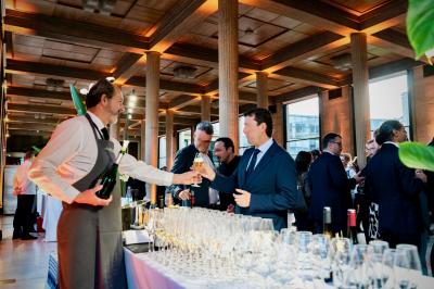 Miniature Traiteur Saint-Cloud (Hauts-de-Seine) - Aux Jardins des Sens #36 Façade illuminée d'un bâtiment élégant au crépuscule, avec un jardin et des invités rassemblés devant.