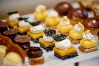 Miniature Traiteur Saint-Cloud (Hauts-de-Seine) - Aux Jardins des Sens #37 Façade illuminée d'un bâtiment élégant au crépuscule, avec un jardin et des invités rassemblés devant.