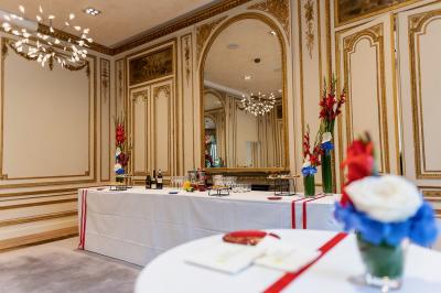 Miniature Traiteur Saint-Cloud (Hauts-de-Seine) - Aux Jardins des Sens #38 Façade illuminée d'un bâtiment élégant au crépuscule, avec un jardin et des invités rassemblés devant.