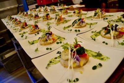 Miniature Traiteur Saint-Cloud (Hauts-de-Seine) - Aux Jardins des Sens #44 Façade illuminée d'un bâtiment élégant au crépuscule, avec un jardin et des invités rassemblés devant.