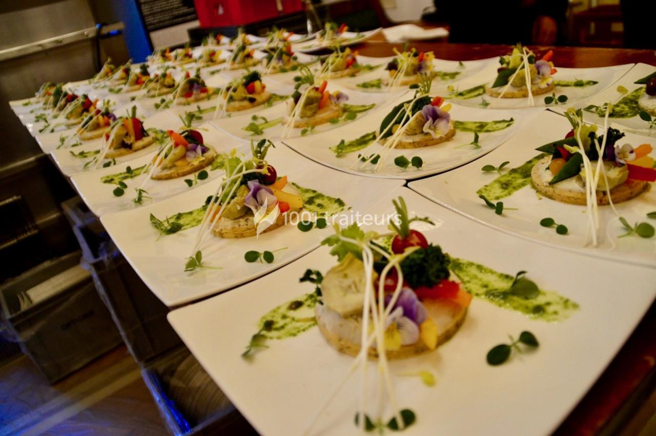 Assiettes dressées avec des entrées colorées, garnies de légumes, fleurs comestibles et sauce verte.
