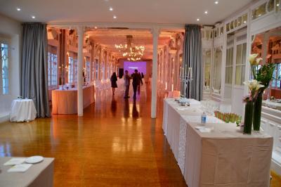 Miniature Traiteur Saint-Cloud (Hauts-de-Seine) - Aux Jardins des Sens #46 Façade illuminée d'un bâtiment élégant au crépuscule, avec un jardin et des invités rassemblés devant.