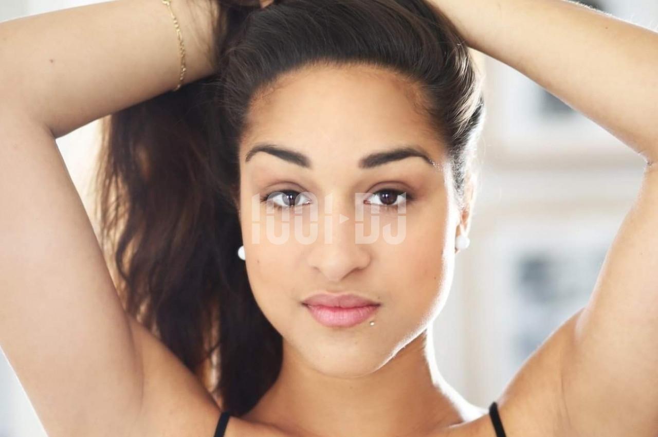 Femme aux cheveux attachés regardant l'objectif, éclairage naturel et arrière-plan flou.