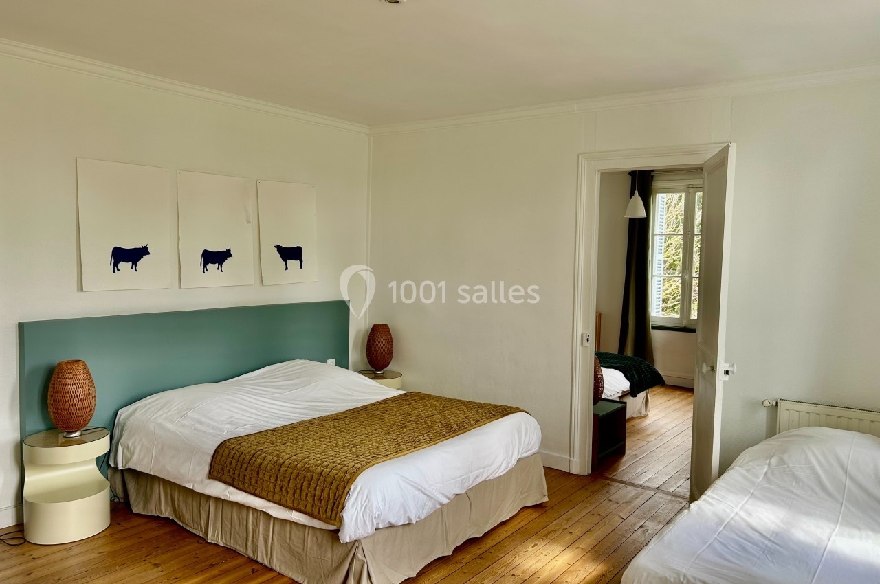 Chambre lumineuse avec lit double, lit simple, parquet en bois, décoration minimaliste et vue sur une autre pièce.