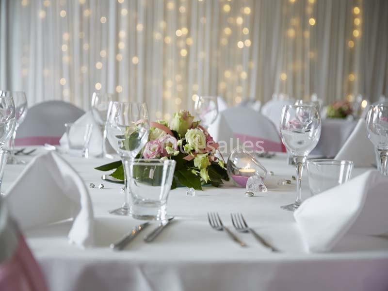 Location salle Noyelles-Godault (Pas-de-Calais) - Novotel Lens Noyelles #15 Table décorée pour un événement avec nappes blanches, verres, couverts et un centre de table floral devant un fond lumineux.