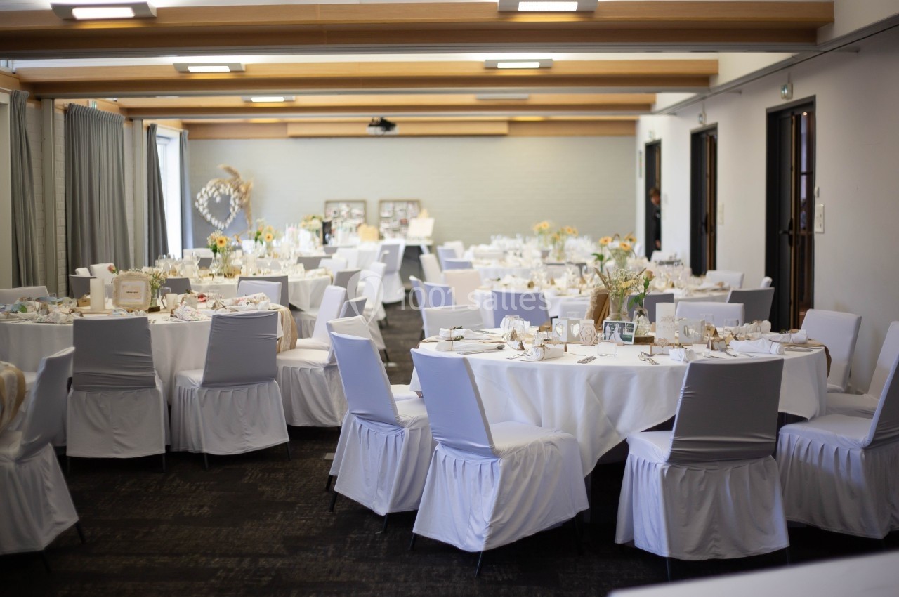 Location salle Noyelles-Godault (Pas-de-Calais) - Novotel Lens Noyelles #7 Salle de réception décorée avec des tables rondes, nappes blanches, chaises houssées et arrangements floraux.