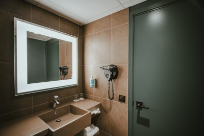 Miniature Location salle Noyelles-Godault (Pas-de-Calais) - Novotel Lens Noyelles #19 Un homme accueille une femme avec une valise dans un hall d'hôtel moderne et lumineux.