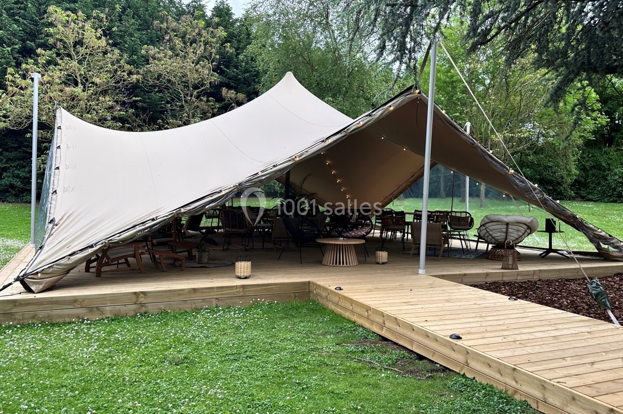 Location salle Noyelles-Godault (Pas-de-Calais) - Novotel Lens Noyelles #5 Tente beige montée sur une terrasse en bois, abritant des meubles de jardin dans un espace verdoyant.