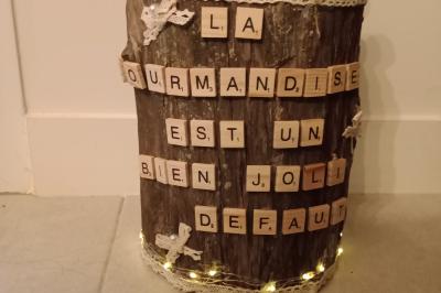Bûche décorative ornée de lettres en bois formant une phrase et de sucettes colorées plantées sur le dessus.